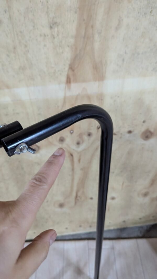 Persona señalando estructura metálica negra en ángulo.