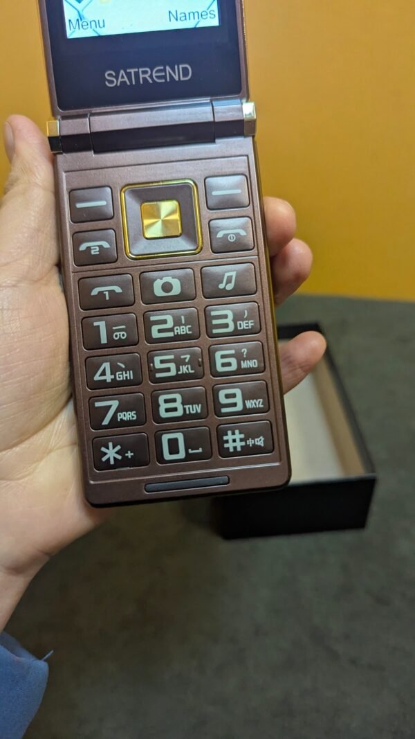 Teléfono plegable antiguo en mano, pantalla y teclado visibles.