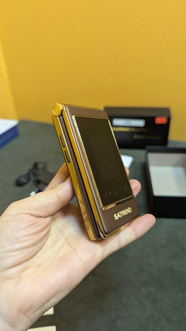 Teléfono plegable dorado sostenido en mano.