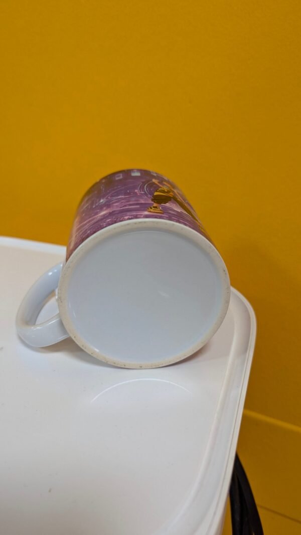 Taza decorativa sobre mesa blanca y fondo amarillo.