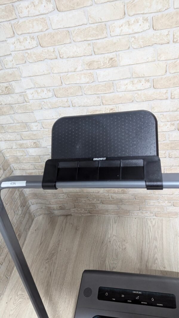 Bicicleta estática DrumFit en habitación con pared de ladrillo.