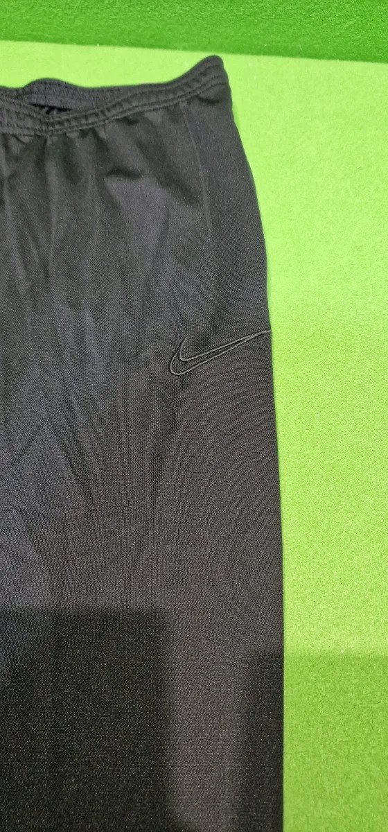 Pantalones deportivos negros sobre fondo verde