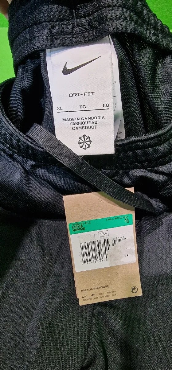 Pantalón deportivo negro, etiqueta de tallas y origen.