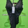 Body de encaje negro en expositor verde