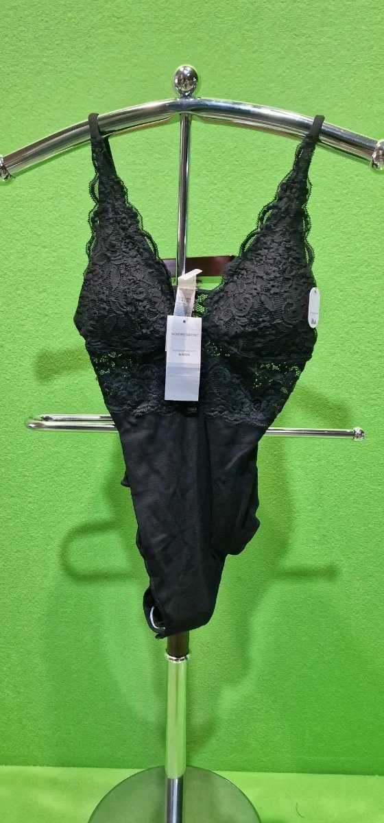Body de encaje negro en expositor verde