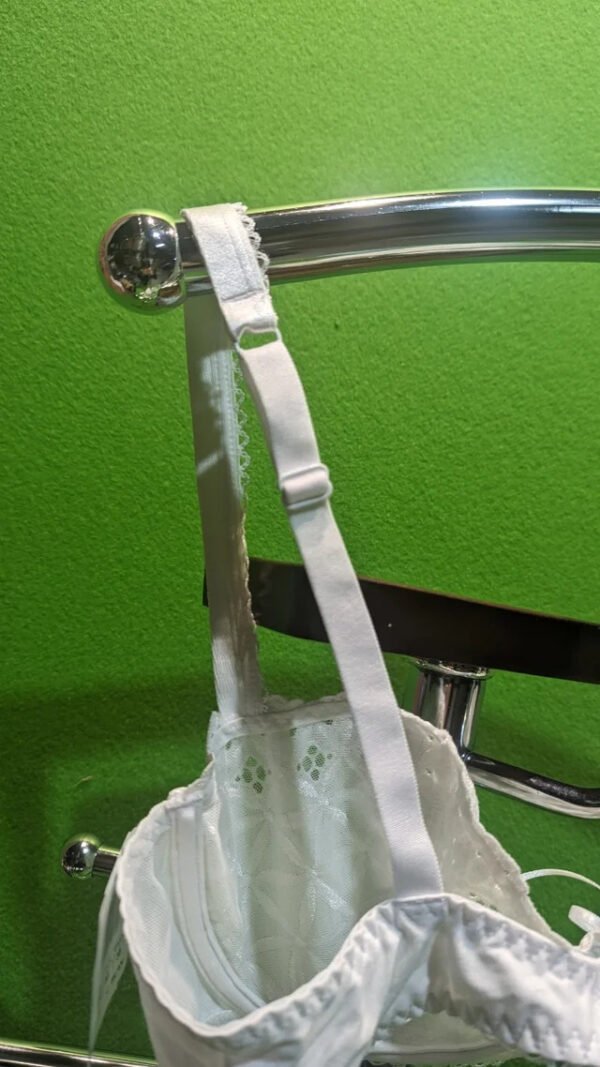 Sujetador blanco colgado en toallero cromado.