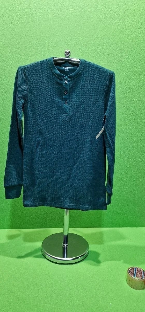 Camiseta verde de manga larga sobre percha metálica.