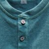 Camisa verde con botones en percha.