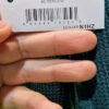 Etiqueta de ropa con código de barras y manos.