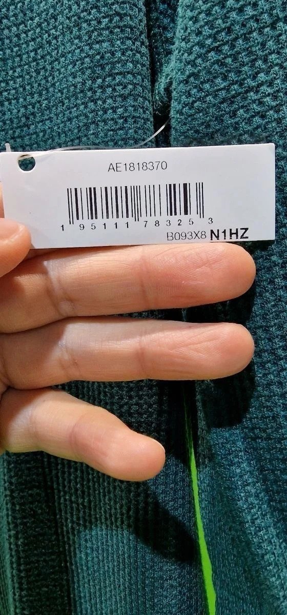 Etiqueta de ropa con código de barras y manos.