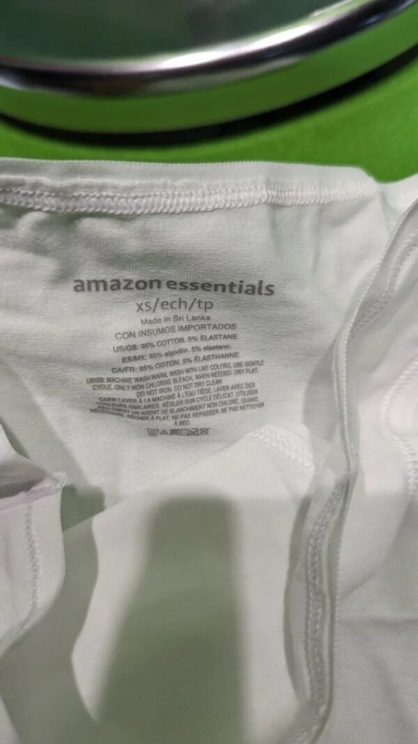 Etiqueta camiseta Amazon Essentials blanca, detalles de fabricación.