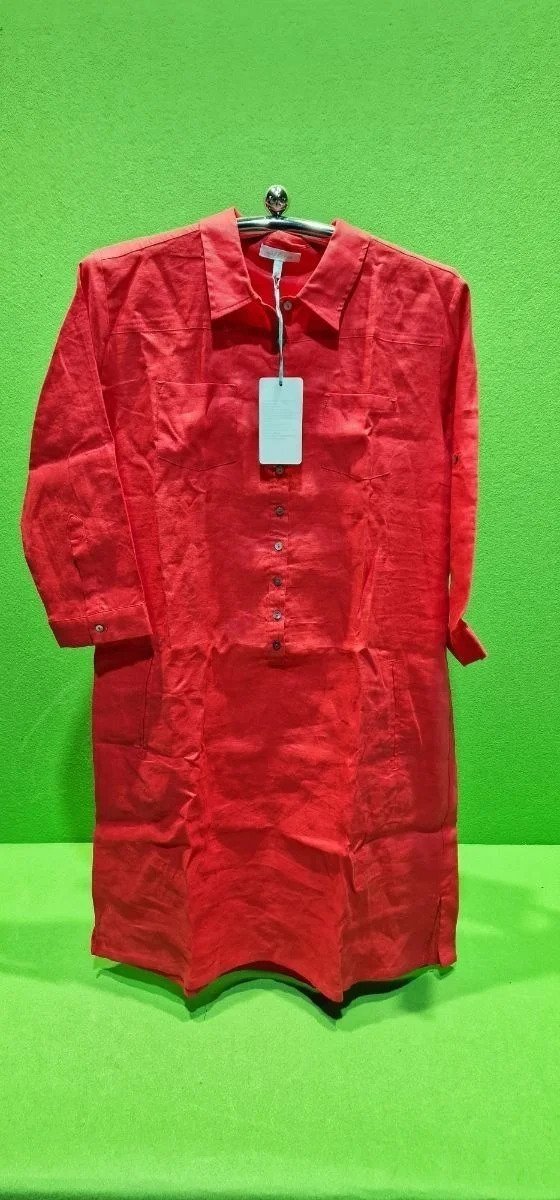 Camisa roja colgada sobre fondo verde.