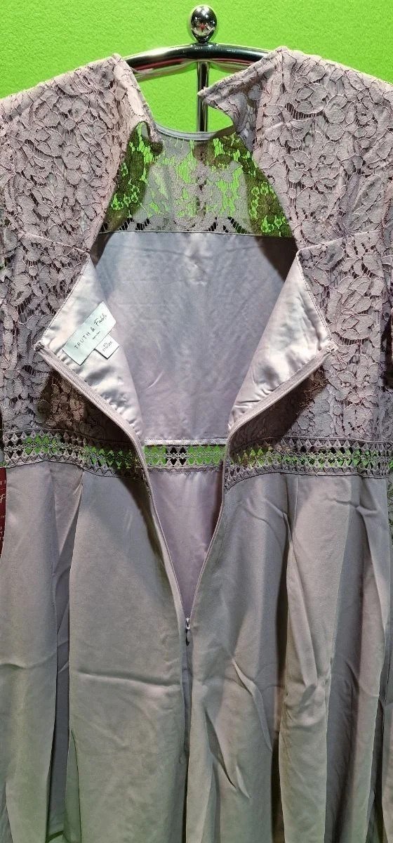 Vestido gris con encaje y cremallera visible.