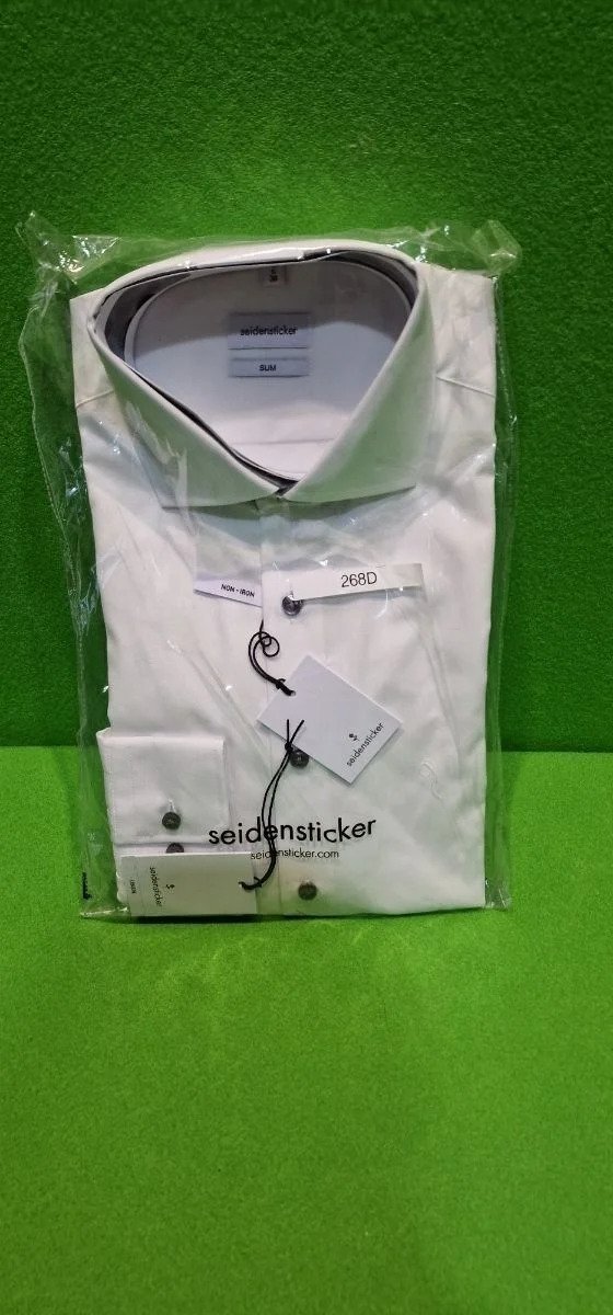 Camisa blanca empaquetada sobre fondo verde.