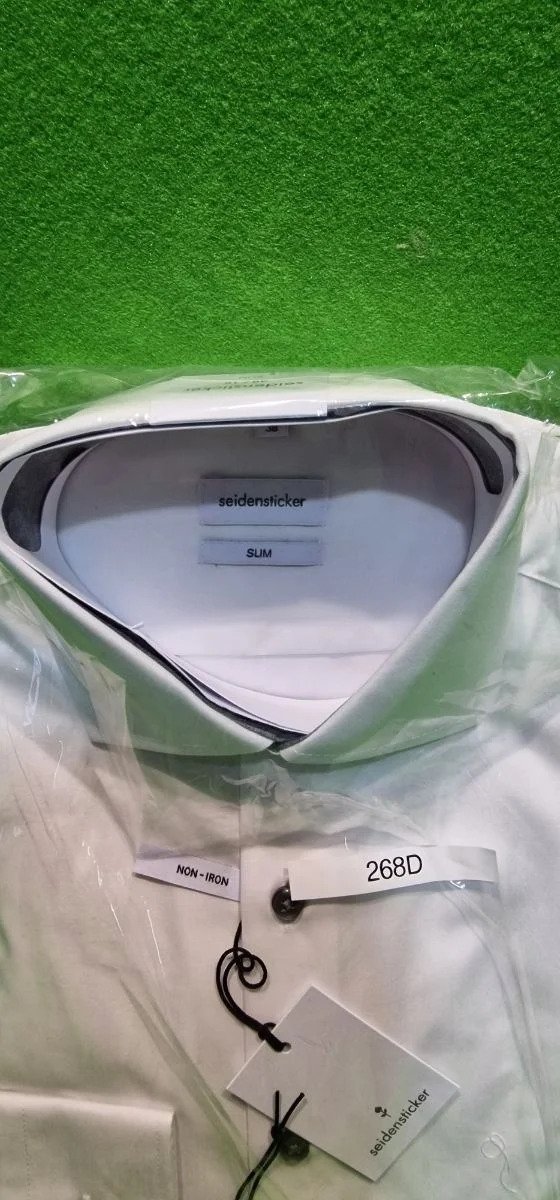 Camisa blanca con etiqueta y collarín visible.