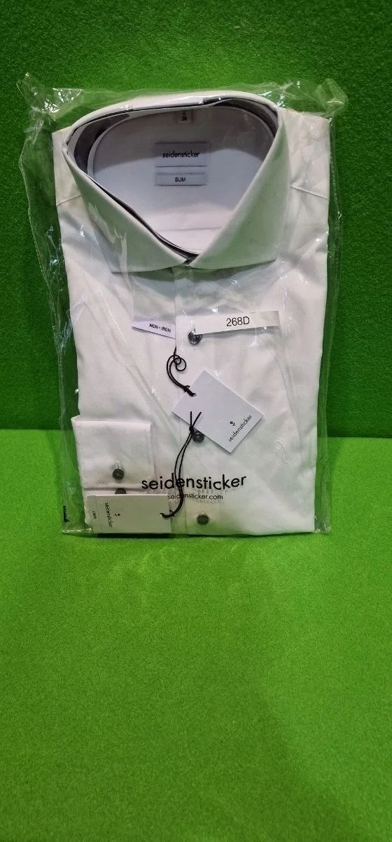 Camisa blanca embalada sobre fondo verde.