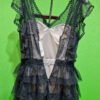 Vestido negro con encaje en maniquí, fondo verde