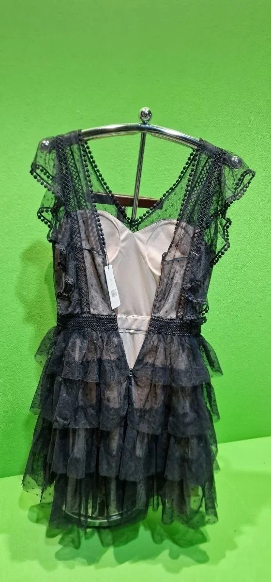 Vestido negro con encaje en maniquí, fondo verde