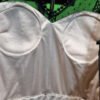 Corset blanco con encaje negro en percha.
