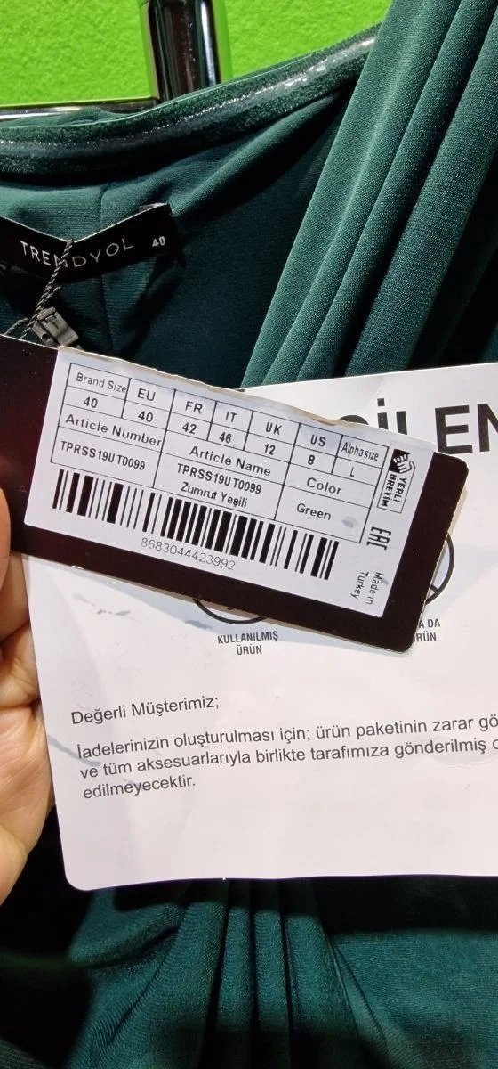 Etiqueta de ropa color verde con códigos y tallas.