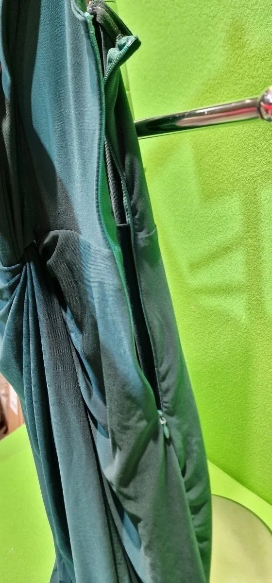 Vestido verde oscuro en percha verde brillante.