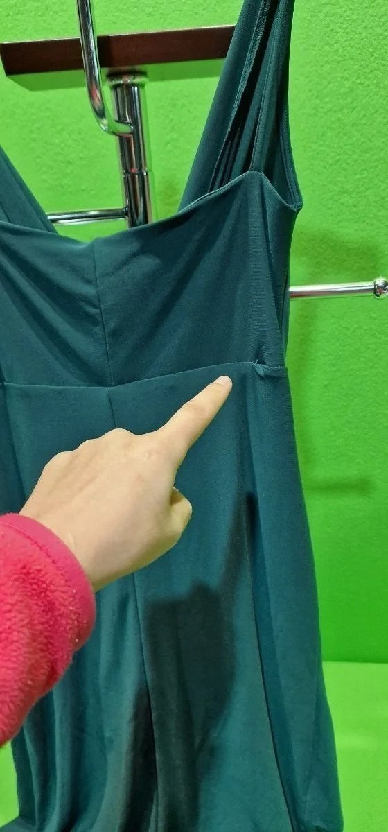 Persona señalando defecto en vestido verde