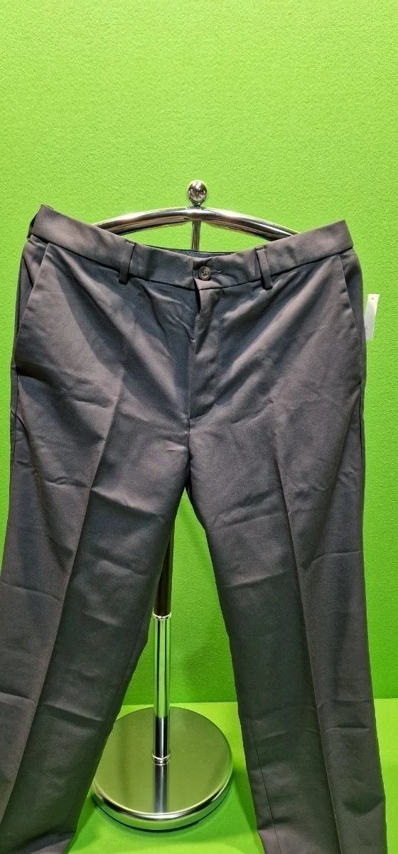 Pantalón gris en percha contra fondo verde.