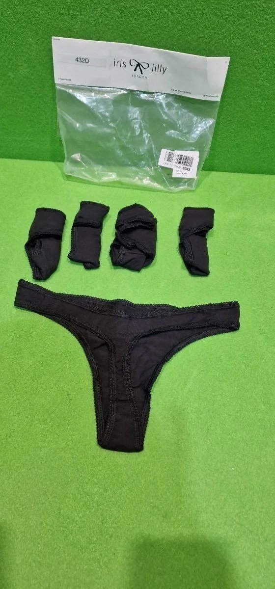 Ropa interior negra con calcetines frente a embalaje.