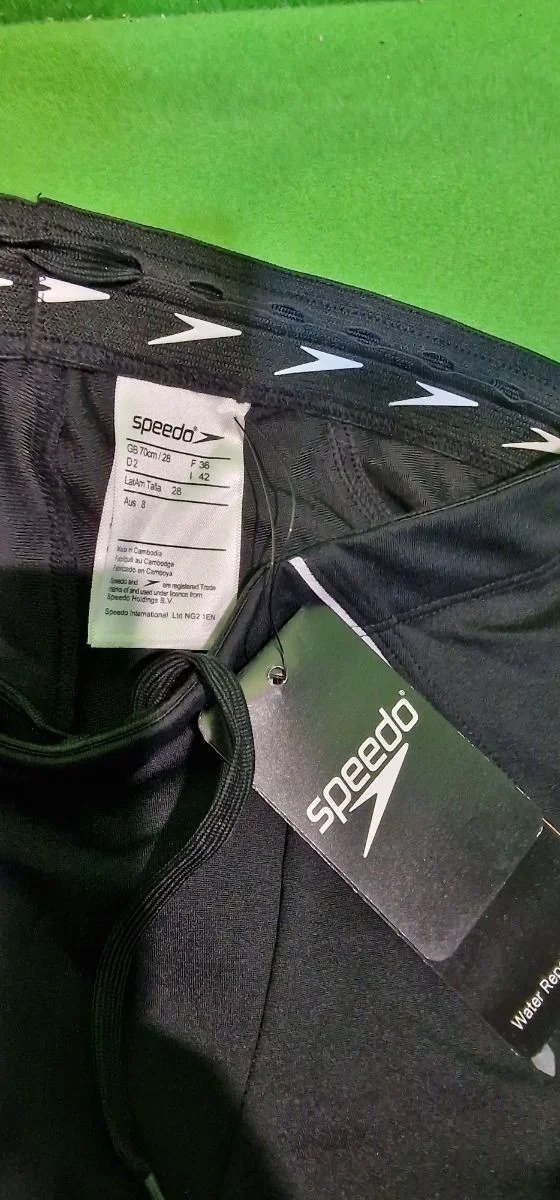 Etiqueta de bañador Speedo negro sobre fondo verde.