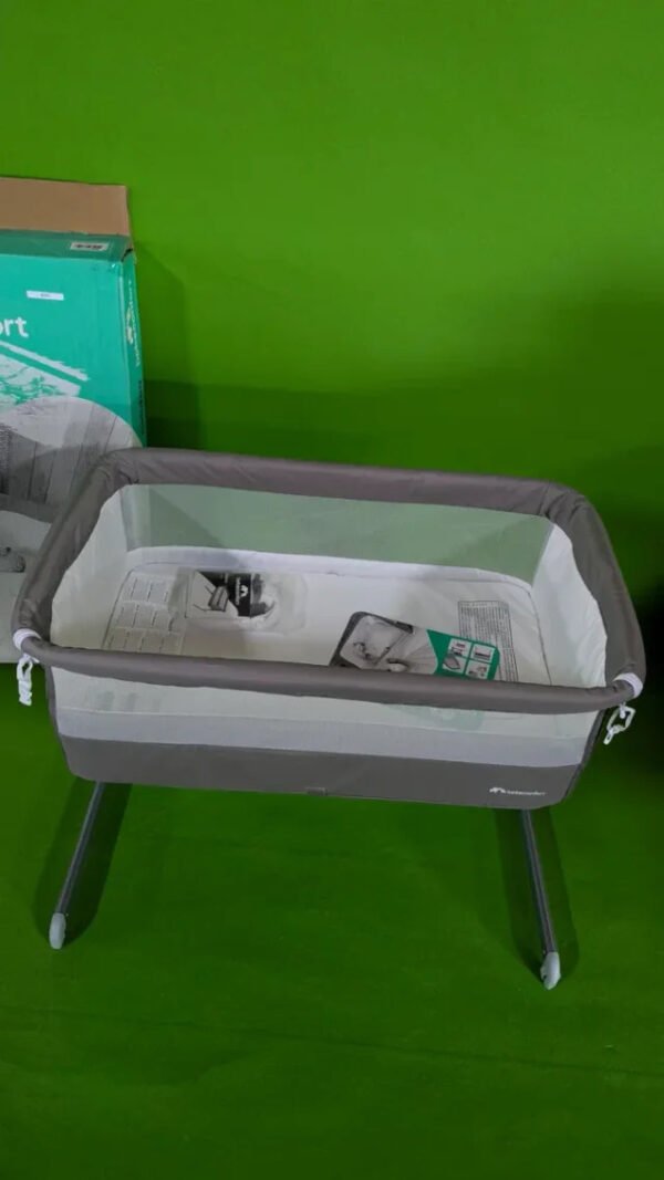 Cuna portátil gris con fondo verde brillante.