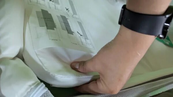 Mano ajustando colchón con instrucciones.